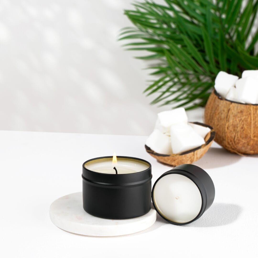Une bougie parfumée naturelle de Niõ en cire de noix de coco, avec des noix de coco et palmiers en arrière plan - nos cires végétales et naturelles - Niõ