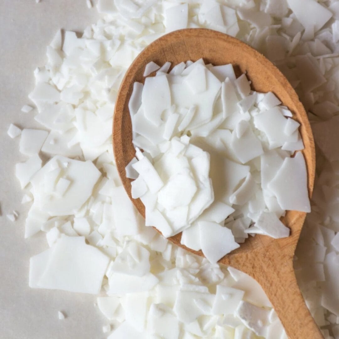 Image de la cire végétale de Soja - une cuillère en bois remplie de cire de soja avant l'utilisation dans une bougie de Niõ - savoir-faire et matière